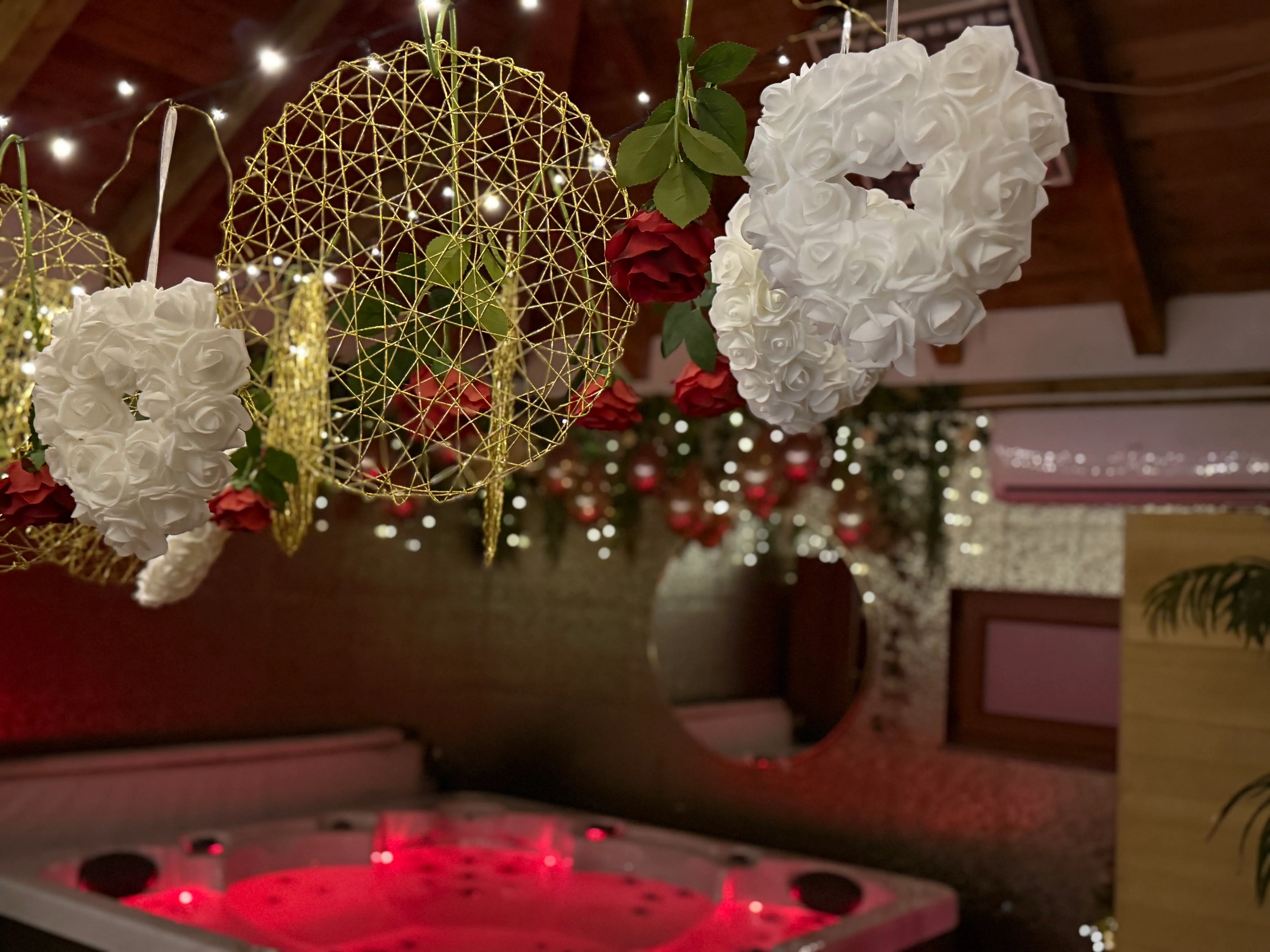White heart ornaments and roses above red-lit jacuzzi