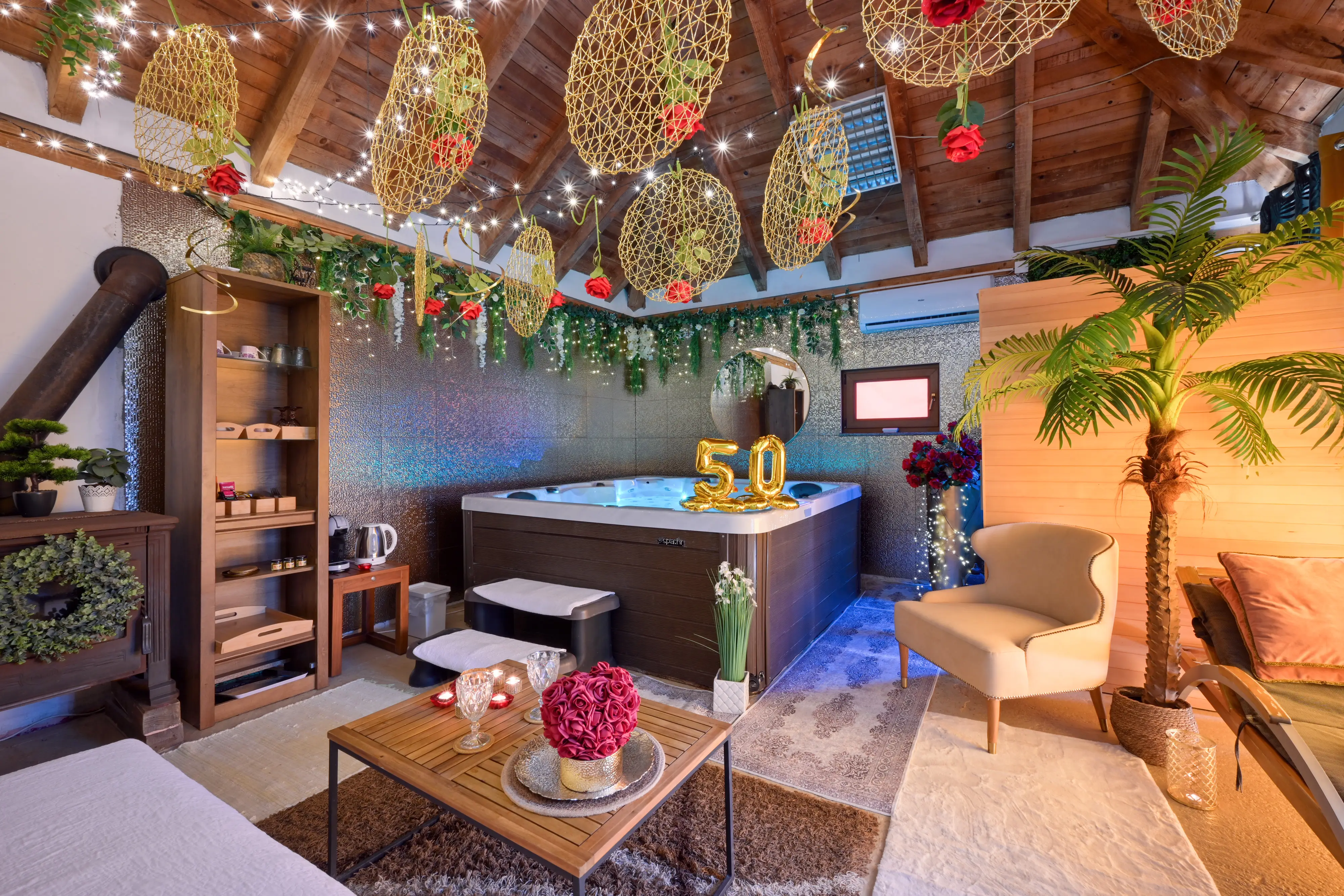 Wide spa room view with jacuzzi, hanging decor, seating, and gold 50 balloons