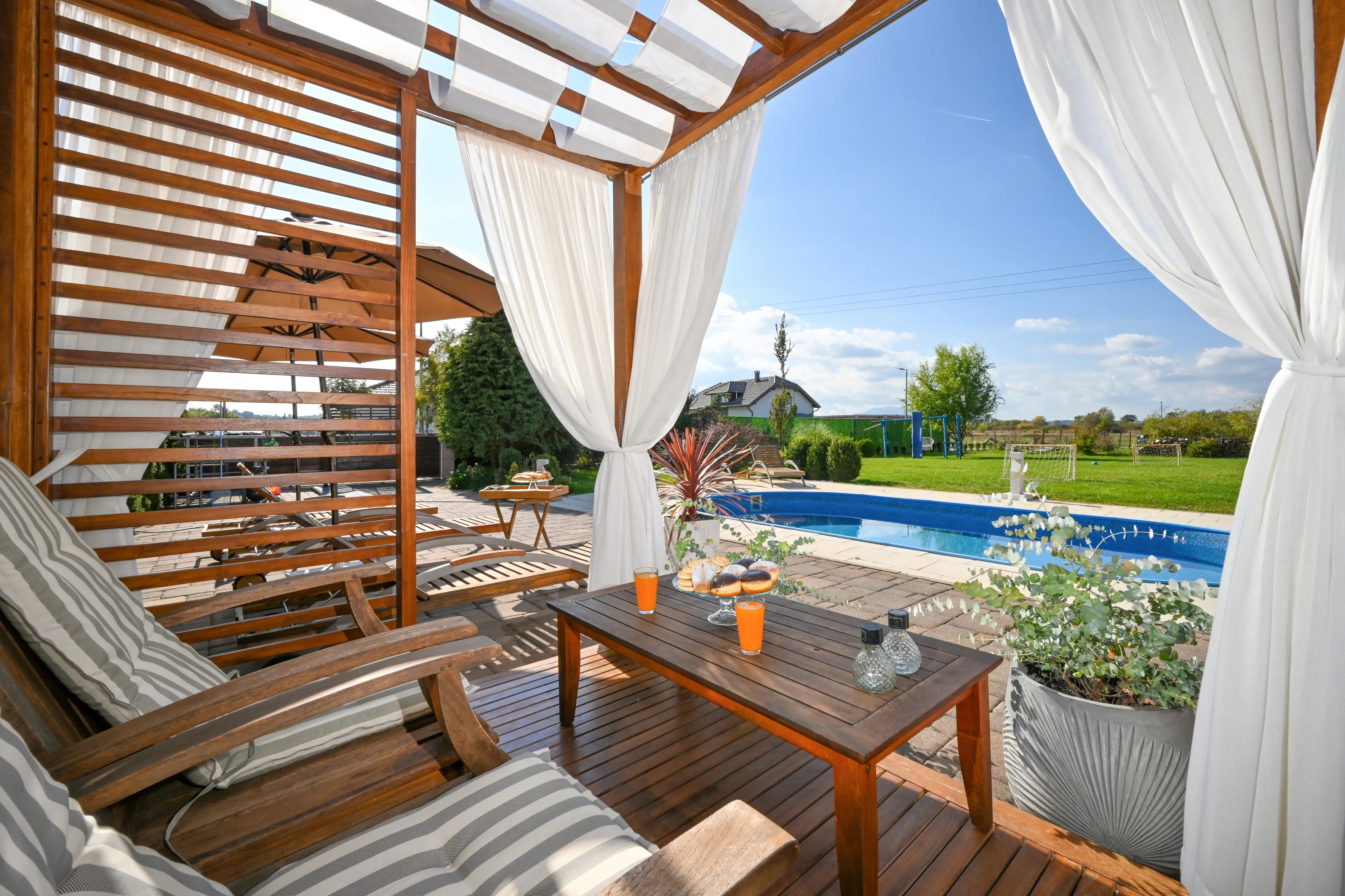 Daytime cabana seating with curtains and pool view