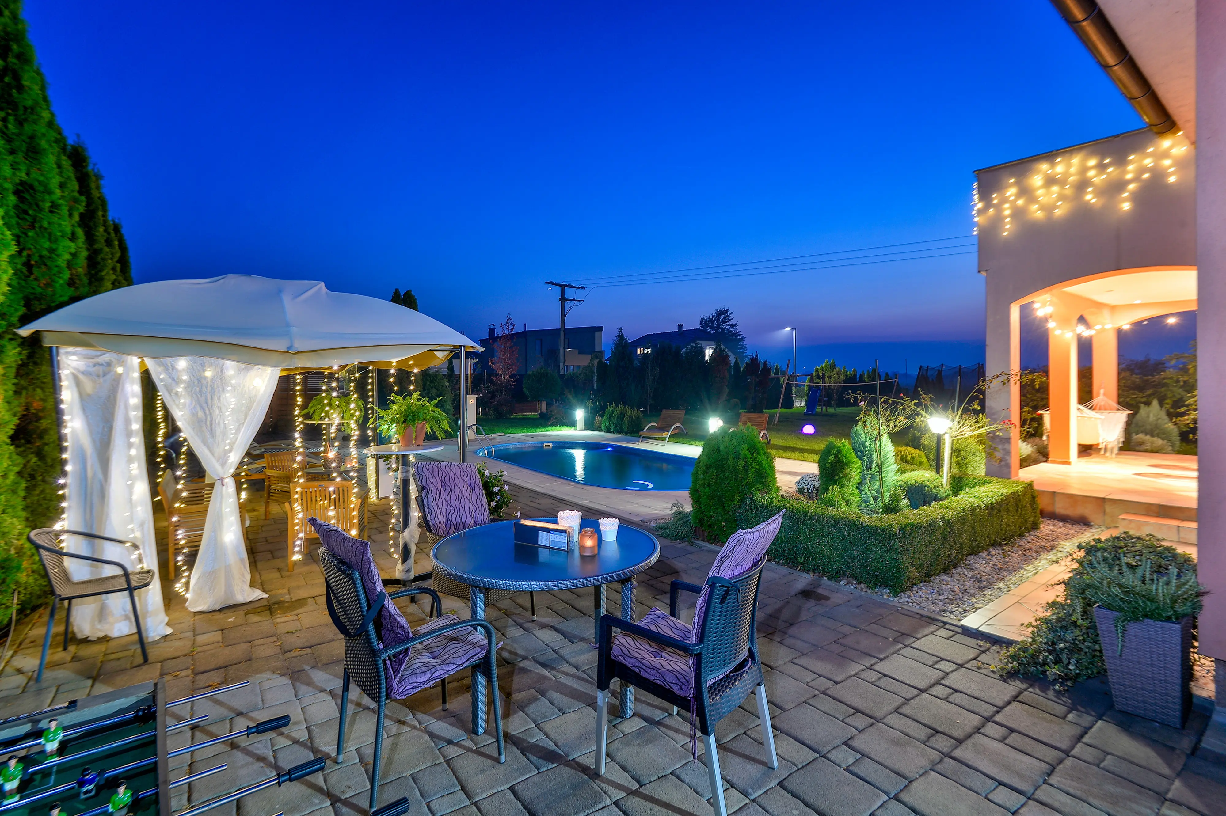 Twilight patio dining set with pool and garden lights