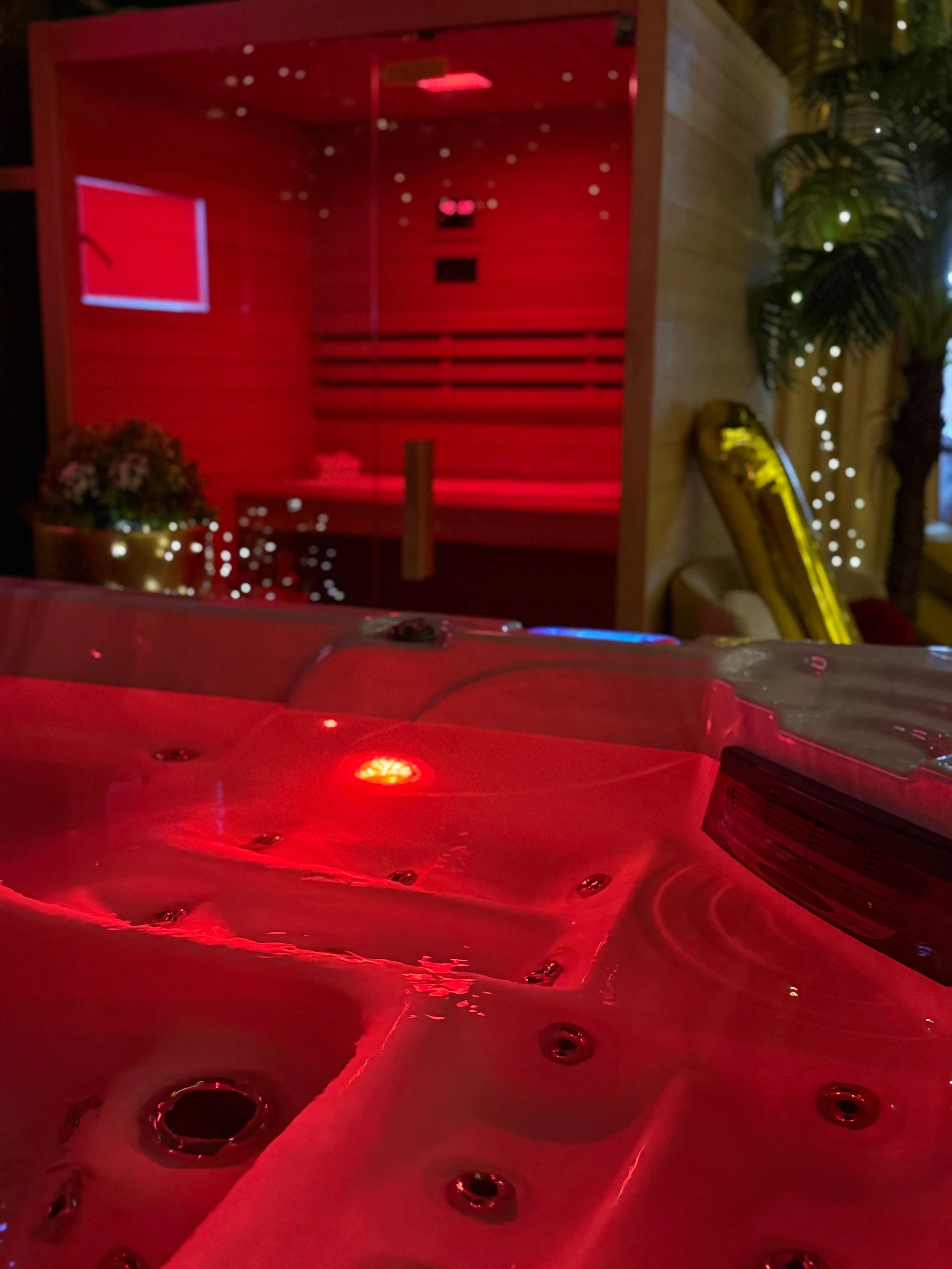 Red-lit jacuzzi in foreground with sauna behind