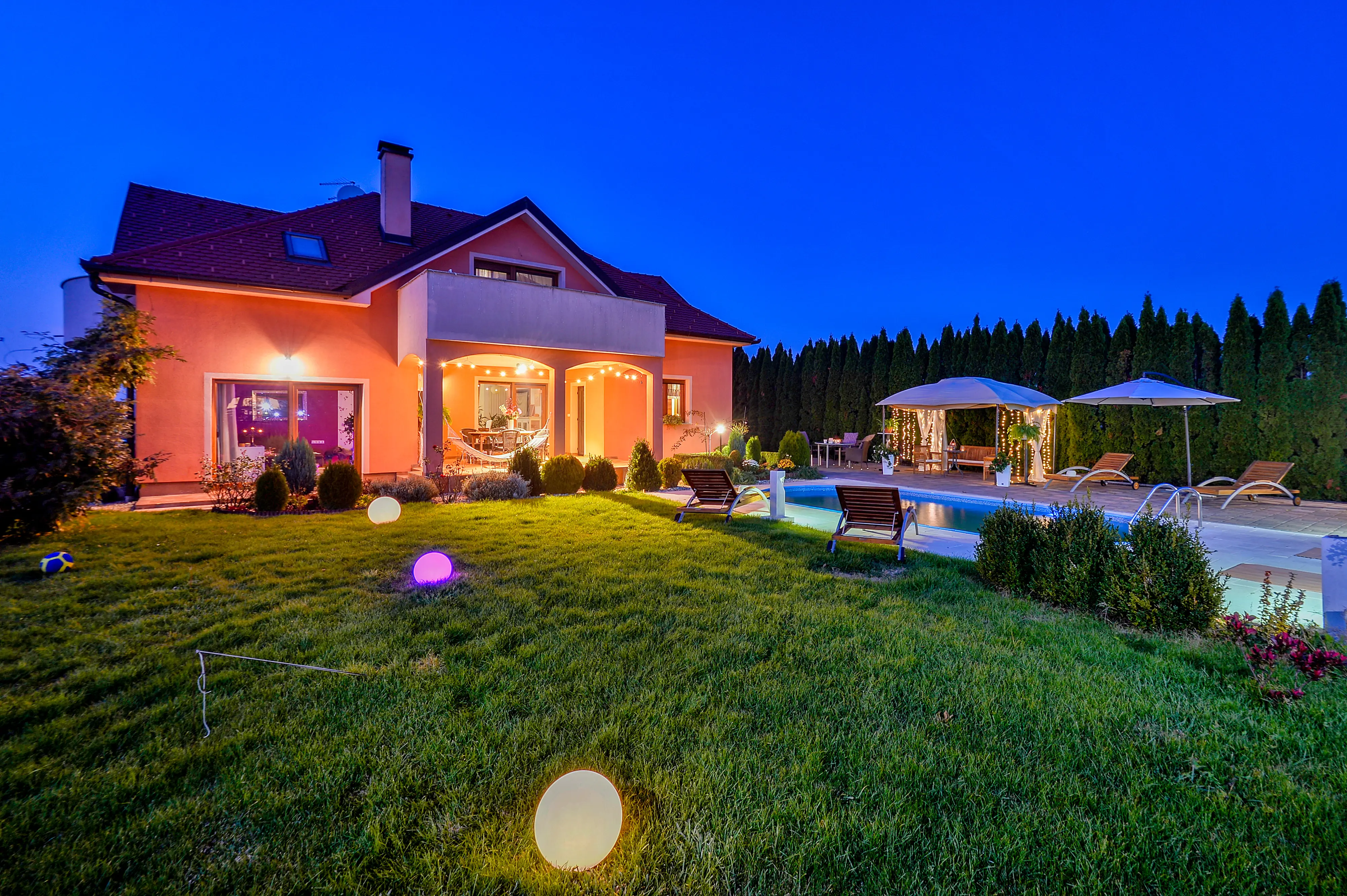 Front facade at blue hour with lawn and pool glow