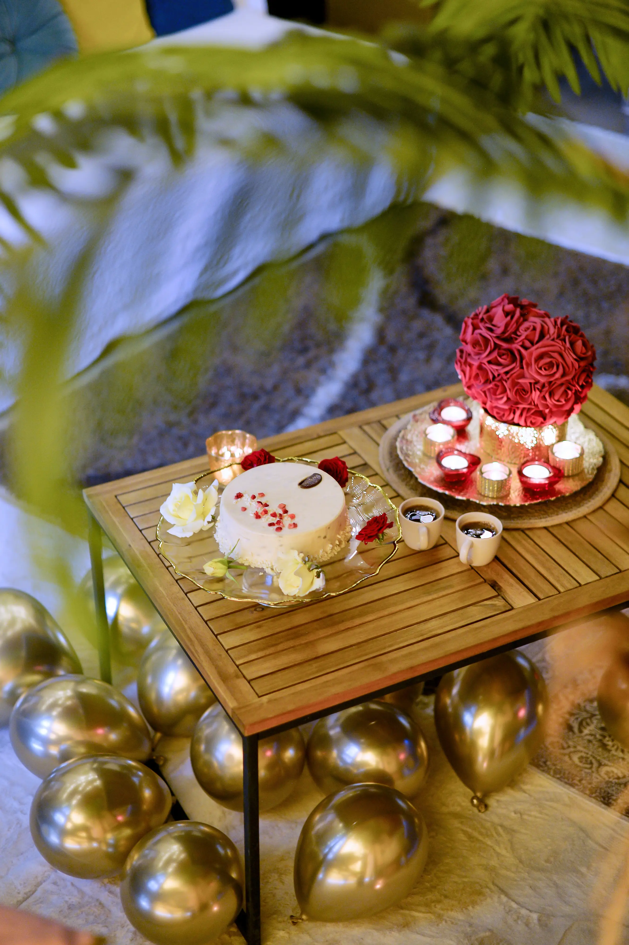 White cake with cups and petals on wooden table